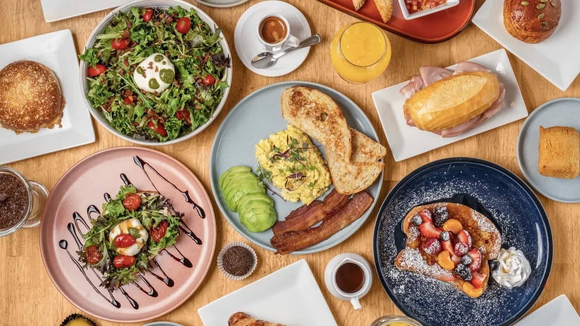 Overhead view of a table with Floré breakfast plates, salad, toast, French toast, a ham sandwich and orange juice