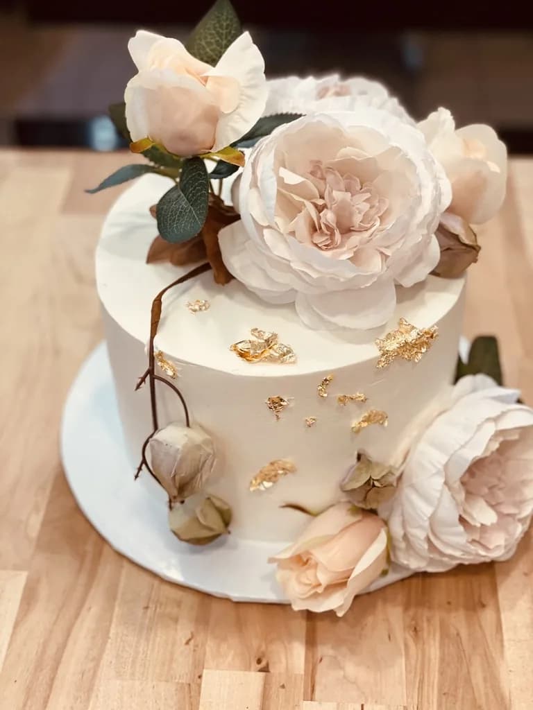 Ivory celebration cake decorated with blush flowers and gold leaf