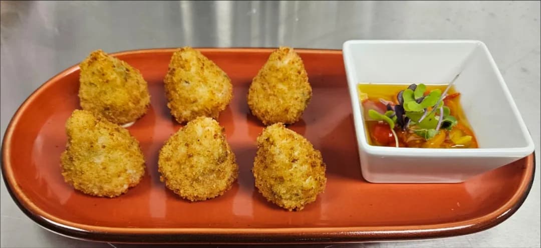Mini coxinhas on a red tray with a dipping sauce