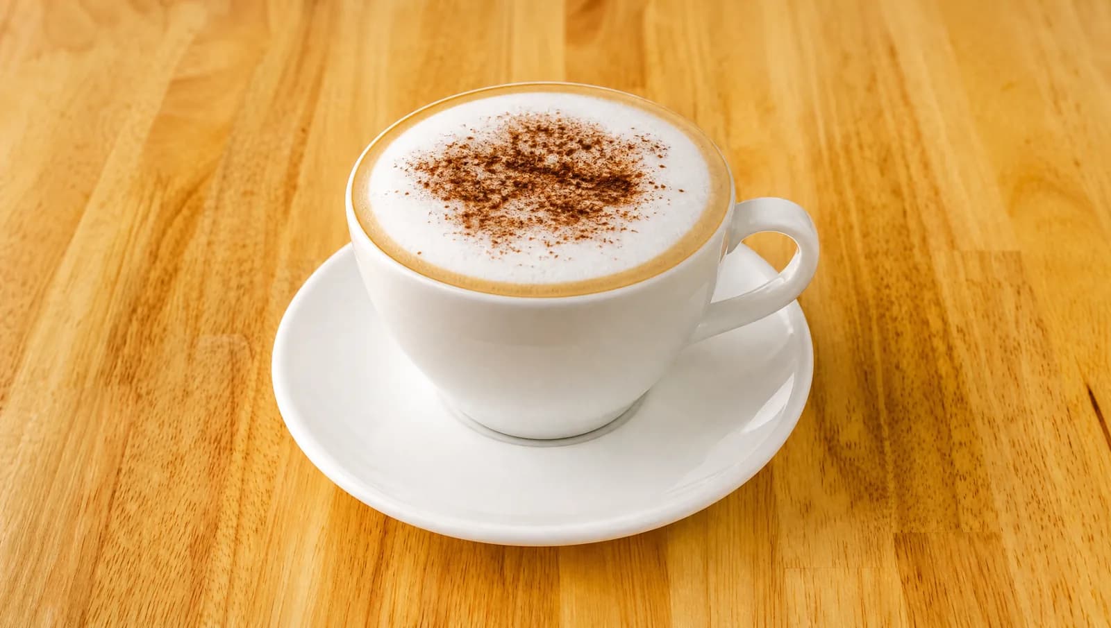 Cappuccino with milk foam and cocoa powder in a white cup at Floré Café & Kitchen